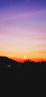 Silhouette landscape against dramatic sky during sunset