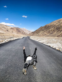 Man riding motorcycle on road against mountain range