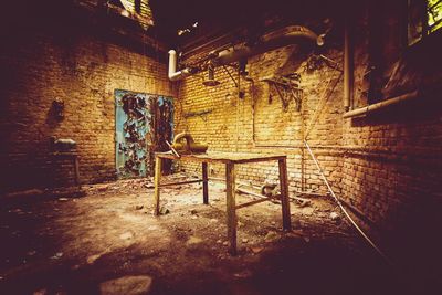 Empty chairs and table against wall in old building