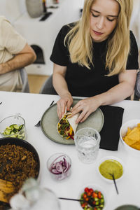 Woman wrapping mexican burrito or taco on plate