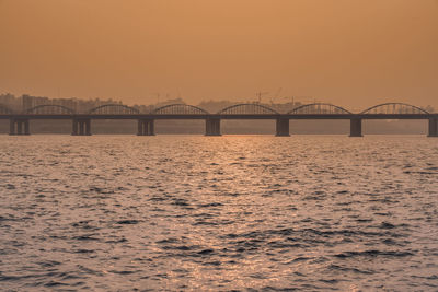 Bridge over river against sky during sunset