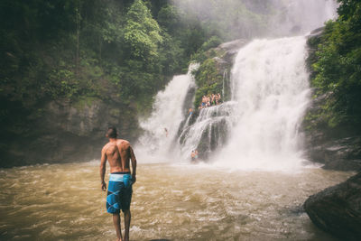 Rear view of man standing against waterfall