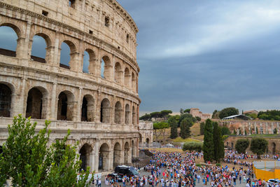 High angle view of tourists at colosseum against cloudy sky