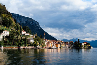 Buildings by lake against sky