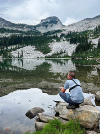 Man sitting on rock by lake