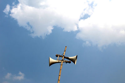 Low angle view of megaphones on bamboo against sky