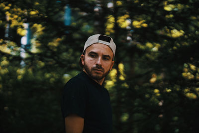 Portrait of young man standing against trees