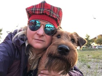 Portrait of woman with dog against sky