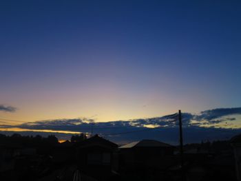 Silhouette houses and buildings against sky at sunset