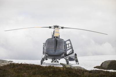 Helicopter landed on snowy mountain ridge.