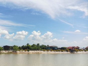 Scenic view of river by buildings against sky