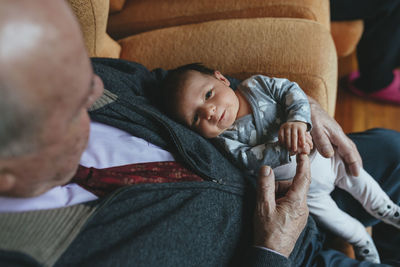 Newborn baby girl on the lap of great grandfather at home