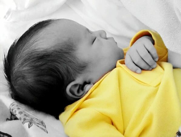 CLOSE-UP OF BABY LYING ON BED