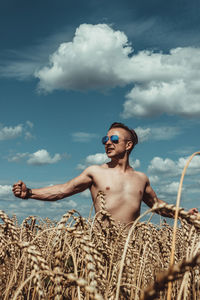 Young man wearing sunglasses sitting on land against sky