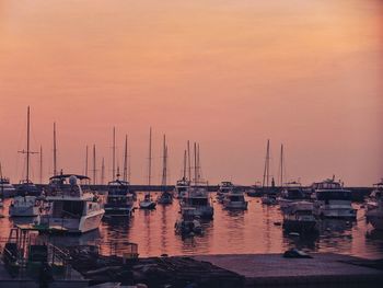 Sailboats moored at harbor during sunset