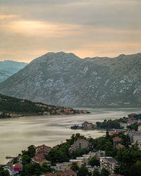 Scenic view of townscape by mountains against sky during sunset