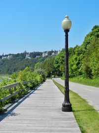 Empty footpath against clear blue sky