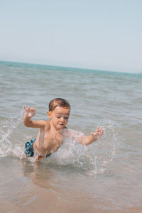 Portrait of shirtless man swimming in sea