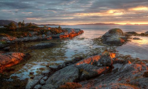 Rocks on shore against sky during sunset