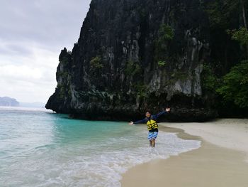 Young man with arms outstretched standing at beach