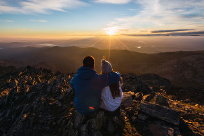 Rear view of men on mountain against sky during sunset