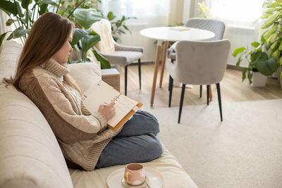 Low section of woman sitting on sofa at home