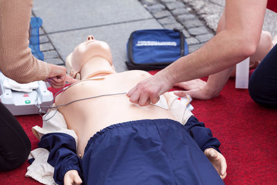 Midsection of instructor teaching paramedic while performing cpr on dummy