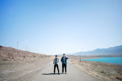 Rear view of couple standing on mountain against clear sky