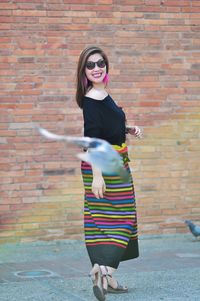 Full length of woman standing against brick wall