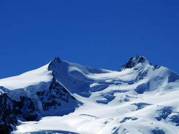 Scenic view of snowcapped mountains against clear blue sky