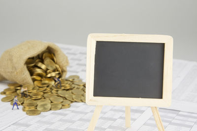 Close-up of coins spilling from sack by blackboard