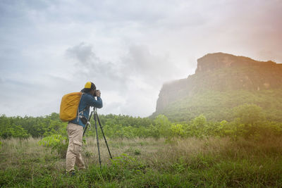 Man photographing on grassy field against sky