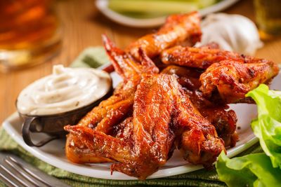 Roasted wings on the plate with sauce close-up.