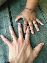 Cropped hands of father and son on table