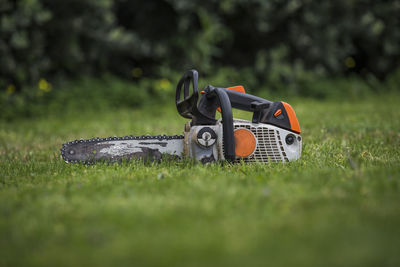 Used chainsaw detail on isolated green grass background.