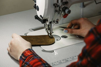 Tailor sewing at workplace. woman hands sewing on machine at workshop. tailoring concept. close-up