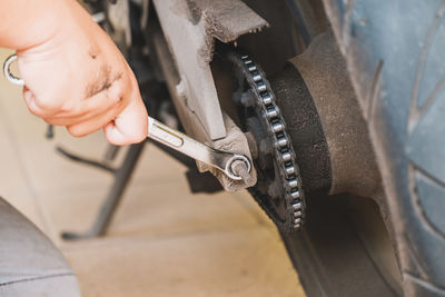 Cropped hand of mechanic repairing motorcycle at garage