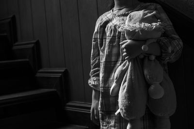 Midsection of girl holding stuffed toy at home