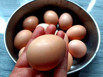 High angle view of hand holding eggs in bowl