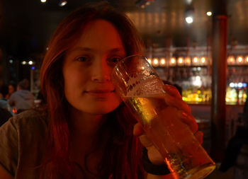 Portrait of young woman drinking beer in bar