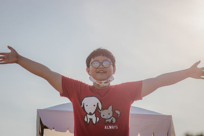 Portrait of boy standing against sky