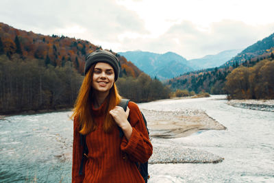 Portrait of smiling young woman standing on mountain during winter