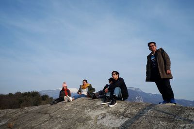 People sitting on road against sky