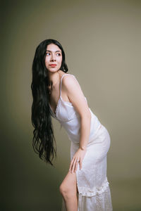 Portrait of young woman standing against gray background