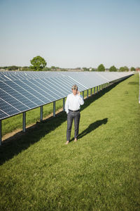 Rear view of man standing on field against clear sky