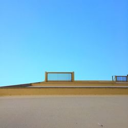 Built structure on sand against clear blue sky