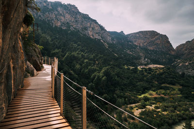 Footbridge amidst mountains against sky