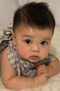 Close-up portrait of cute baby boy on bed