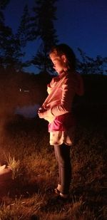 Side view of girl standing on field against sky