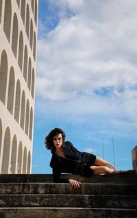 Low angle view of young woman looking away against sky